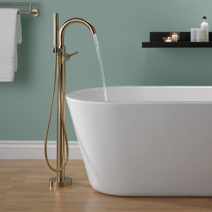 Delta floor mount tub filler with hand shower beside a freestanding tub